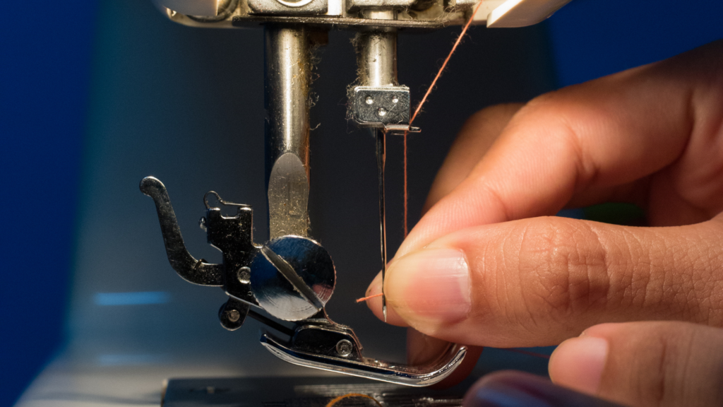 Close up shot of someone inserting a thread into the sewing machine needle